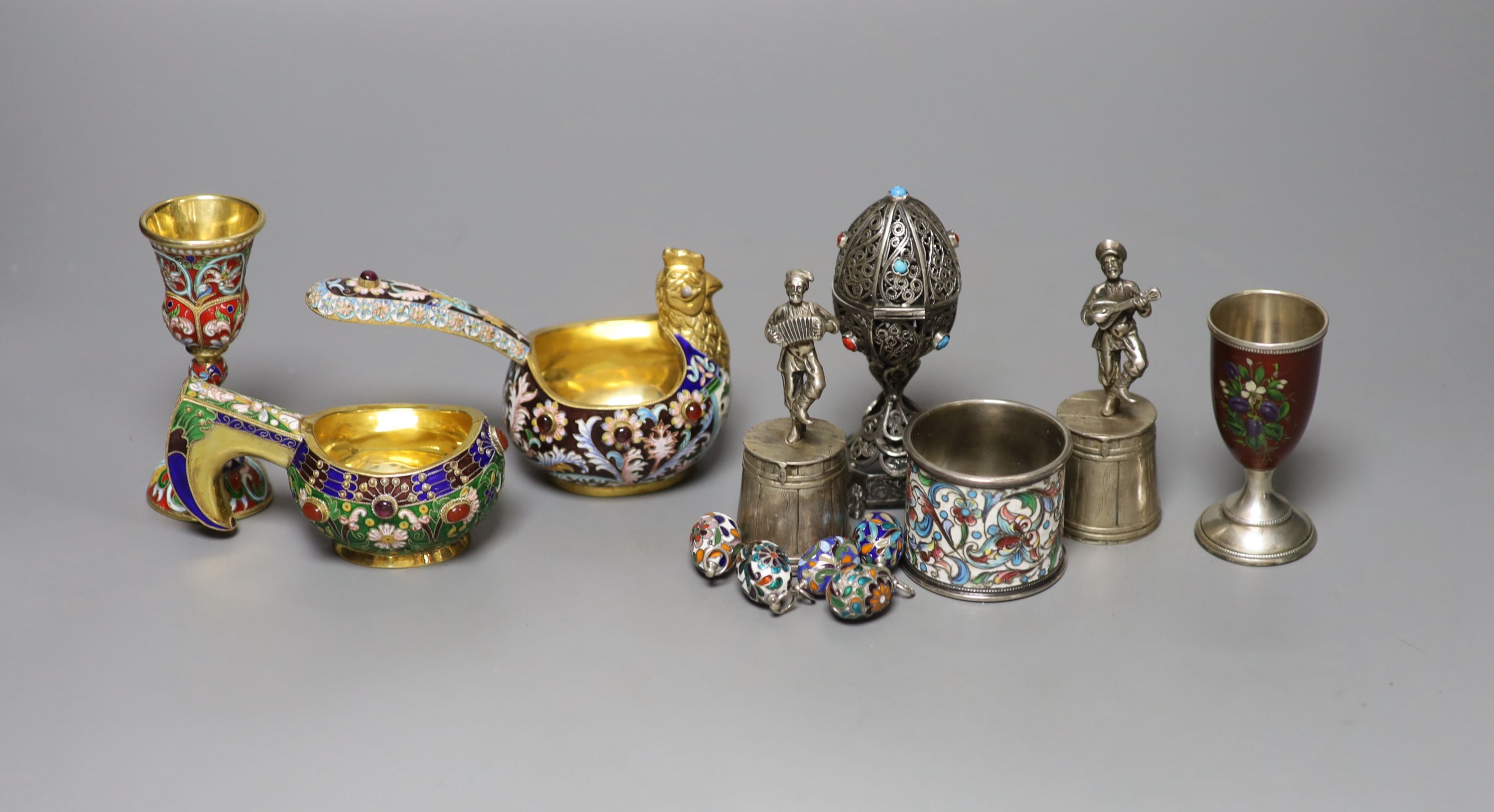 A group of Russian style white metal and enamel items including kovshs, egg pendants and small cups.